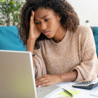 BIPOC student rubs head in frustration in front of laptop